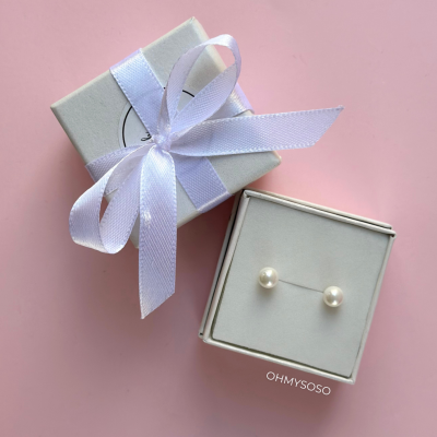 Caixas cinza claro com fita branca e par de brincos de pérola