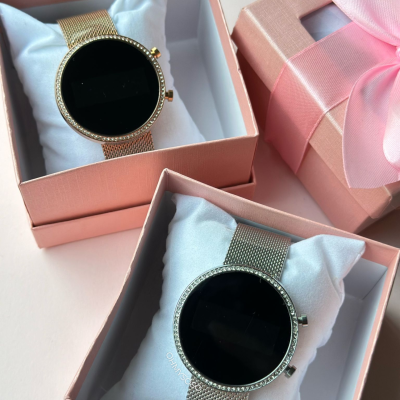 Dois relógios inteligentes em caixas cor-de-rosa com almofadas brancas.