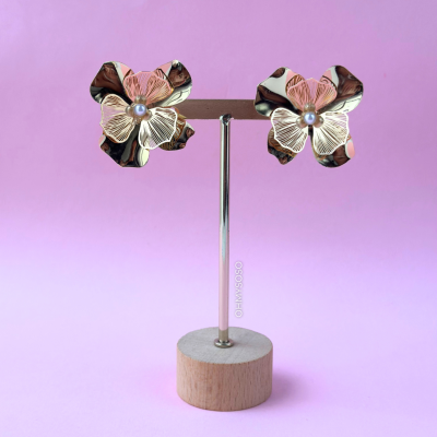 Brincos florais marrons e brancos em suporte com base de madeira