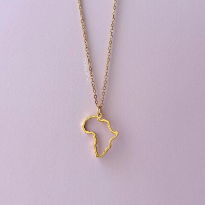 Colar dourado com pendente em forma do continente africano sobre fundo rosa claro