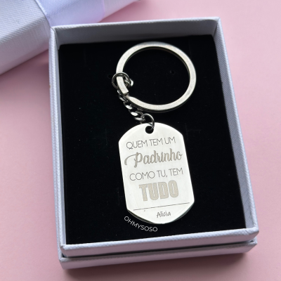 Chaveiro metálico com gravação em caixa preta e branca sobre fundo rosa
