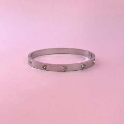 Pulseira prateada com pedras embutidas sobre fundo rosa