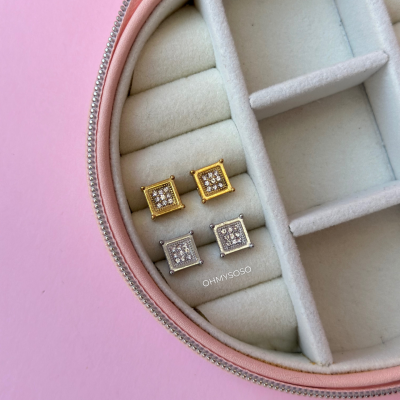 Brincos quadrados dourado e prateado com cristais, na caixa de joias com interior de veludo branco e zíper rosa