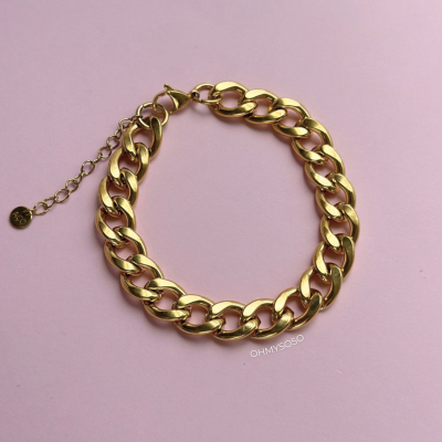 Bracelete dourado de elos grossos com fecho e corrente de ajuste sobre fundo rosa.