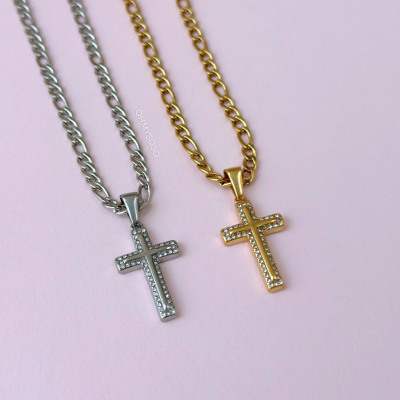 Colares prateado e dourado com cruz cravejada em fundo rosa