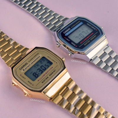 Relógios digitais Casio dourado e prateado com braceletes metálicas em fundo rosa