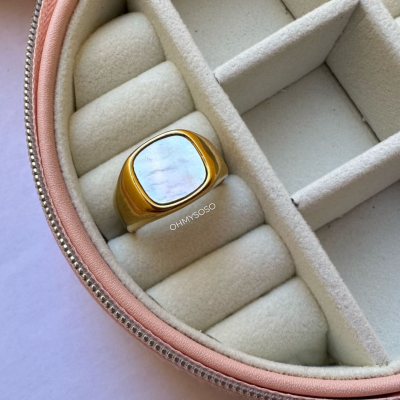 Anel dourado com madrepérola numa caixa de joias de veludo bege