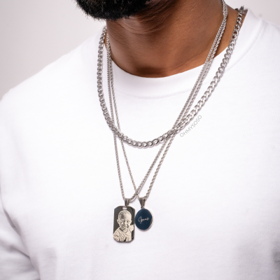 Colar prateado com pendentes gravados, usado por homem com t-shirt branca.