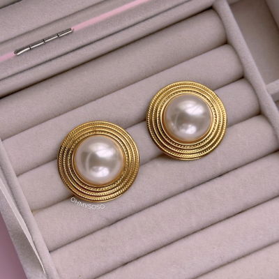 Brincos redondos com pérola central e contorno dourado numa caixa de veludo cinzento