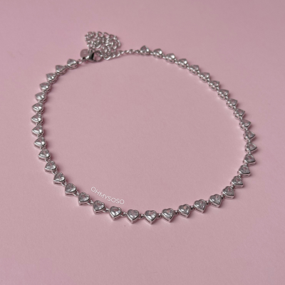 Colar prateado com corações e pedras brilhantes sobre fundo rosa com texto