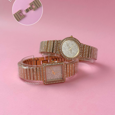 Dois relógios de pulso dourados com pedras brilhantes sobre fundo rosa