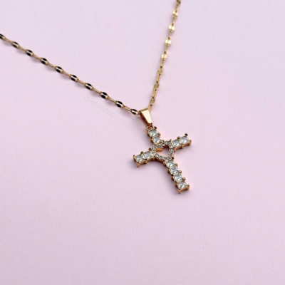 Colar dourado com pendente cruz e pedra e fundo rosa