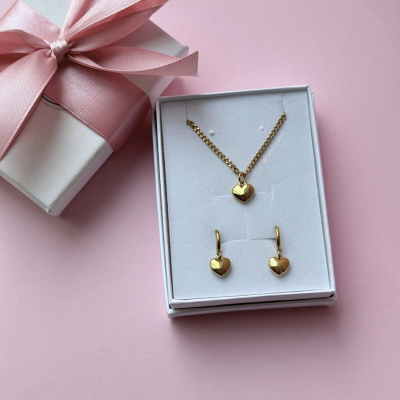 Conjunto de joalharia com colar e brincos de coração dourados em caixa branca com laço rosa