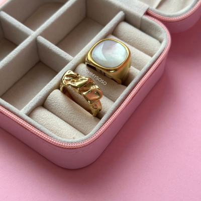 Caixa de joias rosa com dois anéis dourados no interior creme