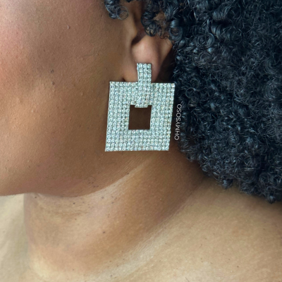 Brinco quadrado com cristais brilhantes no ouvido de pessoa com cabelo encaracolado preto