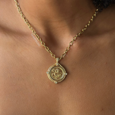 Colar dourado com pendente redondo e corrente de elos ovais.