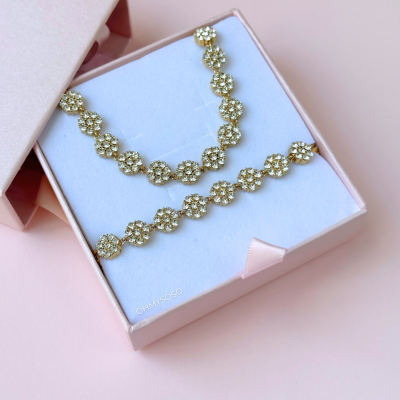 Colar dourado com pendentes em forma de flores em caixa rosa
