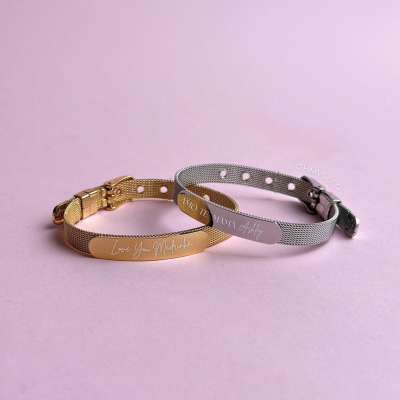 Duas pulseiras metálicas, dourada e prateada, com gravações pessoais sobre fundo rosa