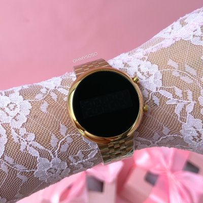 Relógio digital dourado com bracelete metálica e luva branca de renda no pulso