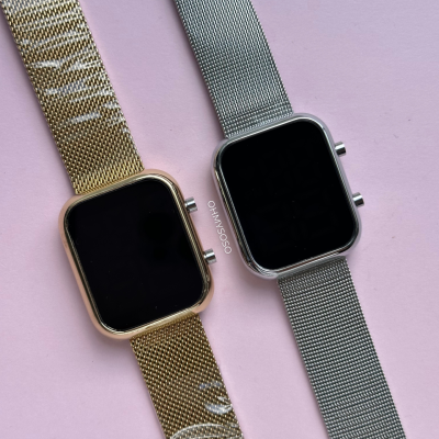 Relógios inteligentes com braceletes metálicas dourada e prateada sobre fundo rosa