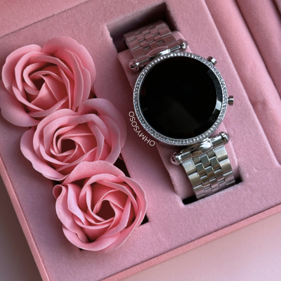 Relógio dourado com bracelete metálica numa caixa rosa com flores decorativas.