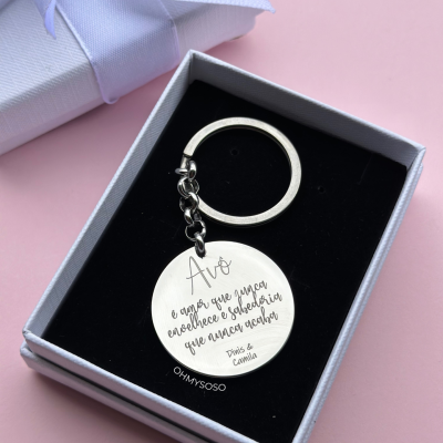 Porta-chaves prateado gravado em caixa preta dentro de uma caixa branca com um laço