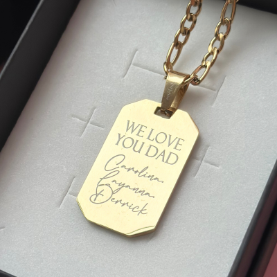 Colar dourado com pendente com gravura, numa caixa de joias preta com interior cinzento.