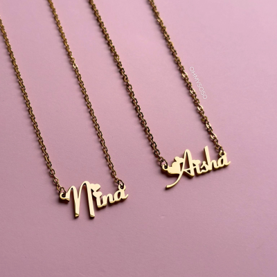 Dois colares dourados com nomes Nina e Aisha em fundo rosa