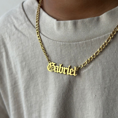 Colar dourado com texto 'Gabriel' em letra gótica numa pessoa com camisola cinza