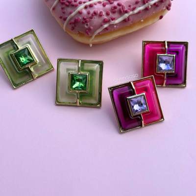 Dois pares de brincos quadrados com pedras coloridas e um donut rosa com granulados