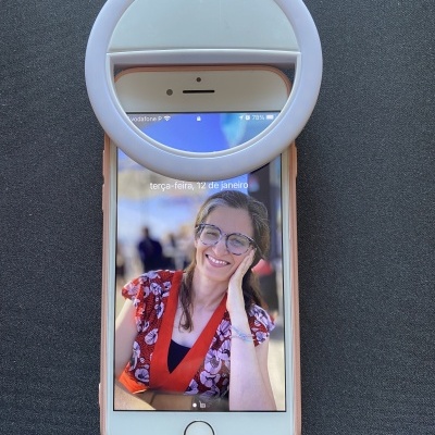 iPhone com capa cor de rosa e luz de anel branca sobre superfície preta