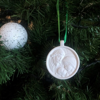 Ornamento natal branco medalhão com figuras em relevo pendurado numa árvore de natal