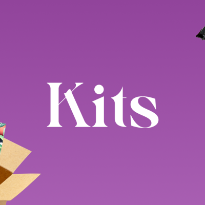 Caixas de cartão abertas com diversos produtos em fundo roxo e texto 'Kits' ao centro