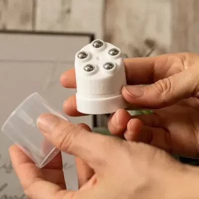 Dispositivo branco com rolamentos metálicos e tampa translúcida nas mãos de uma pessoa