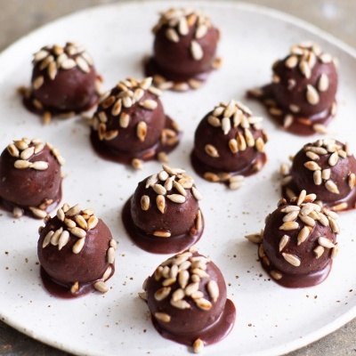 Doze trufas de chocolate com sementes tostadas num prato branco