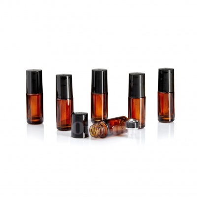 Frascos pequenos de vidro âmbar com tampas pretas, um deitado com tampa removida