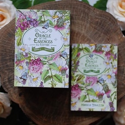 Duas caixas de baralhos potentes com arte floral colocadas sobre madeira e rodeadas por rosas brancas