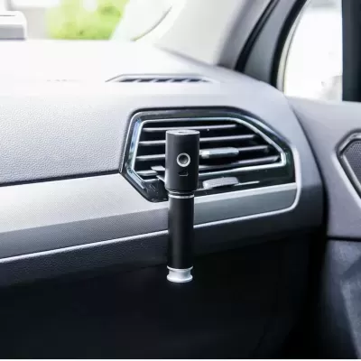 Aparelho preto cilíndrico fixado na saída de ar do painel de um carro