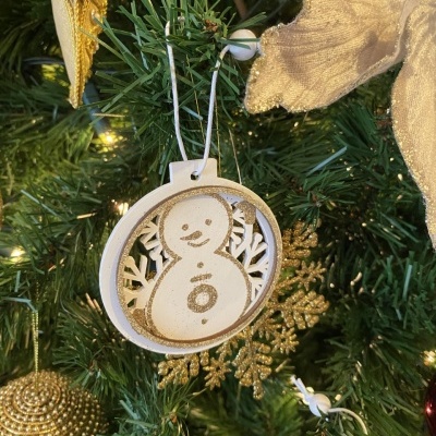 Enfeite de Natal de madeira com boneco de neve branco e dourado pendurado numa árvore de Natal