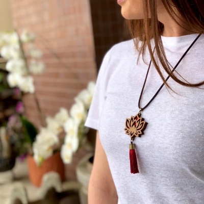 Colar com pendente de flor de madeira e tassel vermelho sobre t-shirt branca.