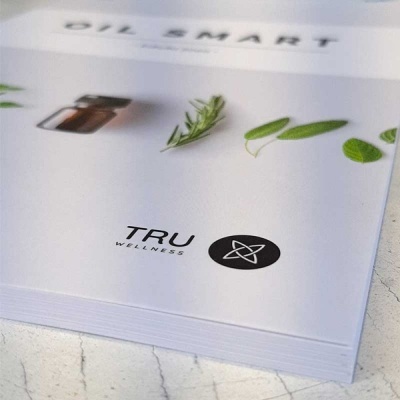 Folheto branco com o título OIL SMART, folhas verdes, frasco de vidro âmbar e logo TRU WELLNESS