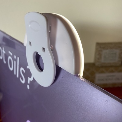 Clipe branco preso na borda de um tablet roxo com texto branco