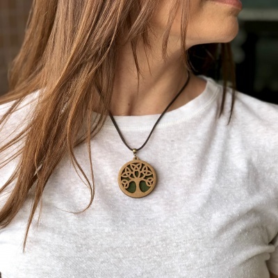 Colar pendente redondo em madeira com padrão de árvore, cordão preto e fundo verde escuro