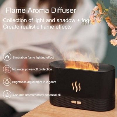 Difusor de aroma preto simulando chamas numa mesa de madeira clara com plantas ao fundo