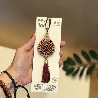 Colar olfativo de madeira castanho com franja vermelha na embalagem branca