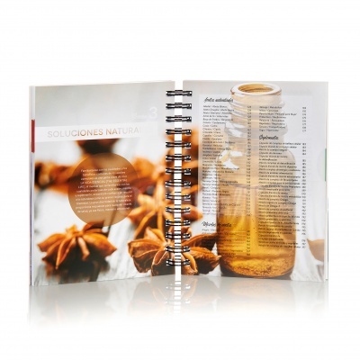 Livro aberto com páginas mostrando anis-estrelado e frasco de vidro com líquido ambar.