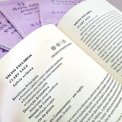 Página aberta de livro com texto sobre Sálvia Esclareia e livros lilás ao fundo.