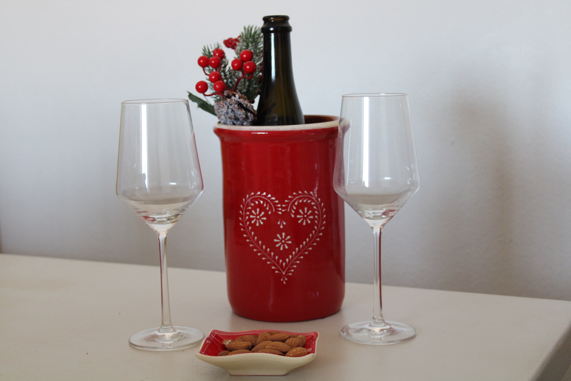 Winecoller Garrafa numa cubeta vermelha com decoração de coração, dois copos de vidro e prato com amêndoas