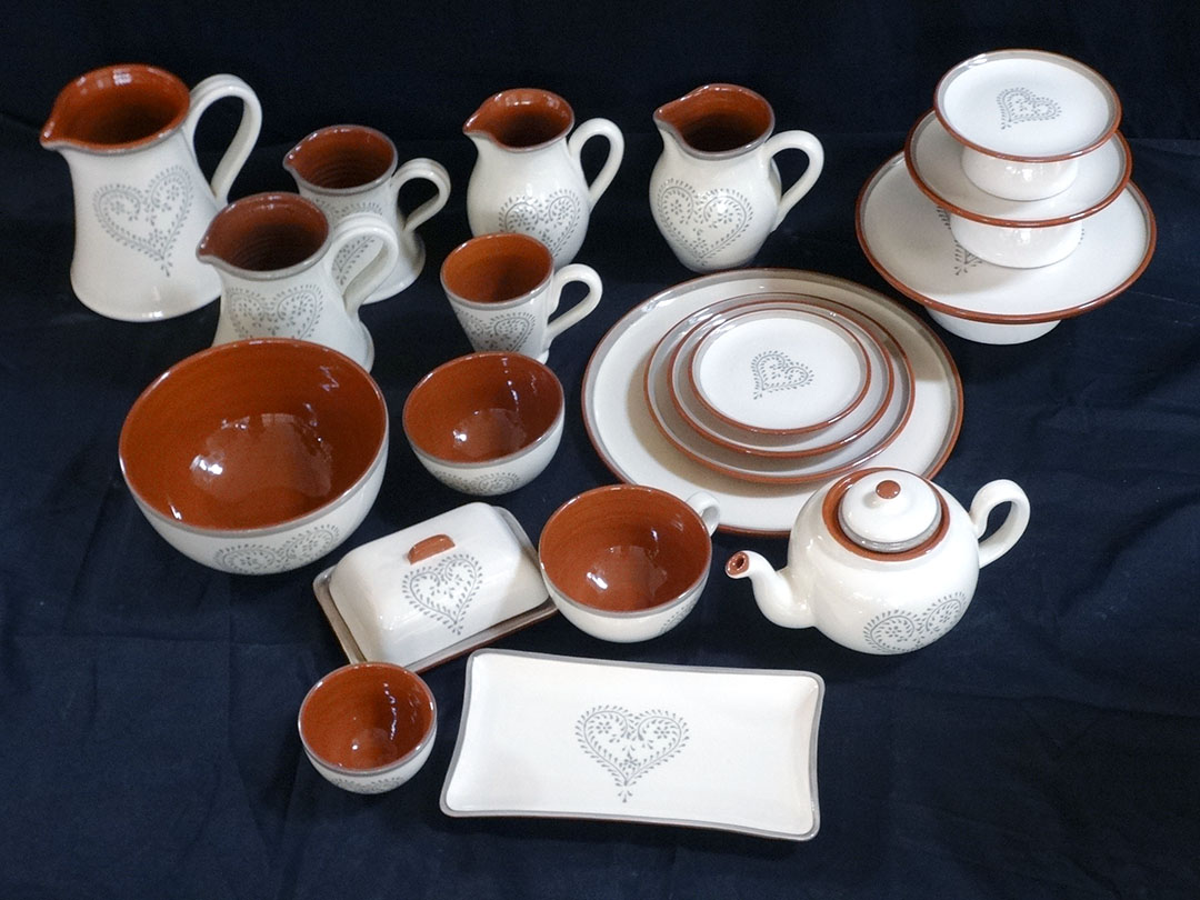 Conjunto de loiça em cerâmica branca e castanha com desenhos de corações