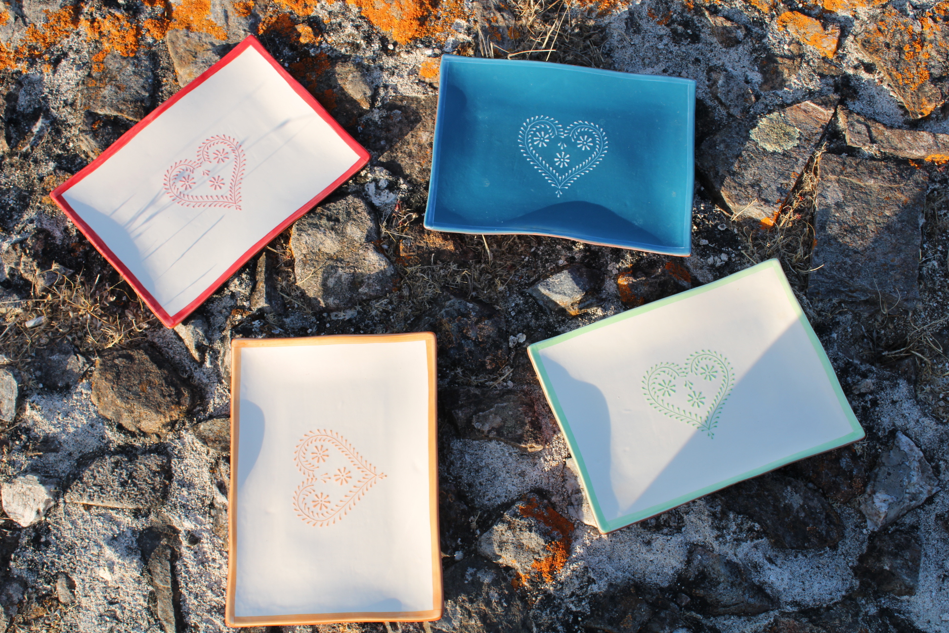 Travessa Ondulada Grande Quatro pratos de cerâmica coloridos com corações decorativos em pedra com líquenes laranja